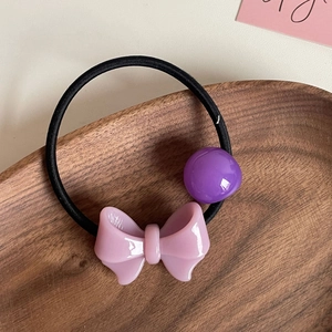 Elastico per capelli con fiocco rosa e perla viola su vassoio di legno, stile dolce