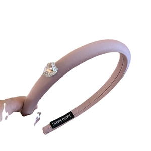 Pink satin padded headband featuring a rhinestone heart jewel and handmade label detail