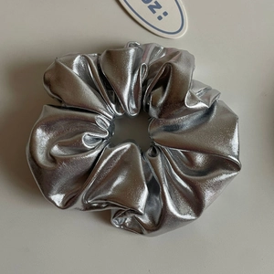 Macro shot of large silver scrunchie with metallic mirror finish and pleated fabric texture
