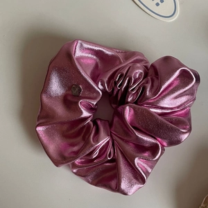 Detail of laser metallic texture scrunchie in rose pink with heart pendant