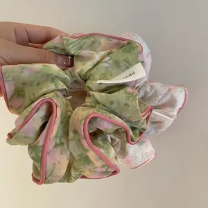 Chouchou floral oversize avec roses roses, feuilles vertes et bordure en soie délicate