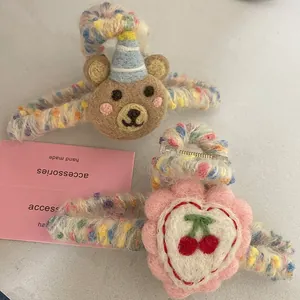 Close-up of wool felt brown bear and cherry flower hair claws with knitted texture