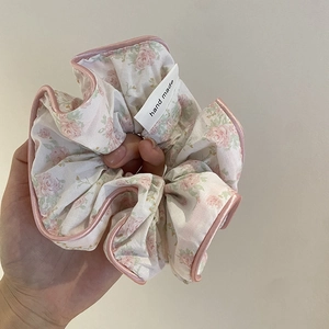 Vue détaillée d'un chouchou floral avec liseré en satin rose et étiquette tissée à la main