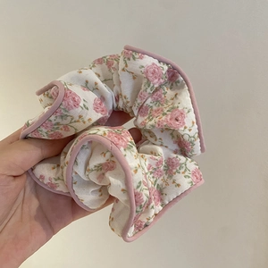 Détail d'un chouchou floral avec motifs de roses roses et finitions délicates