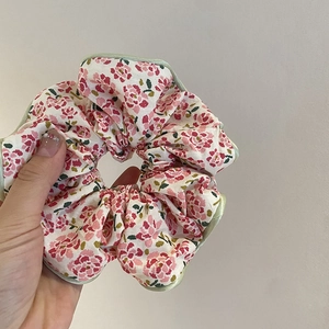 Détail d'un chouchou floral avec fleurs roses et bord vert, montrant sa texture