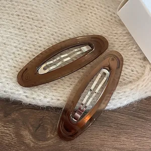 Paire de barrettes en acrylique ambre rétro avec pince en métal sur un support tricoté