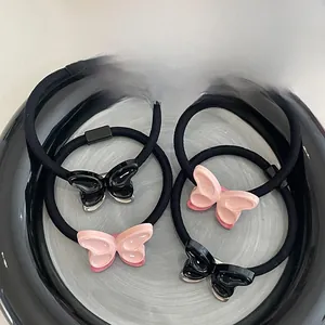 Détail de chouchous papillon 3D mignons en rose et noir sur un plateau en céramique