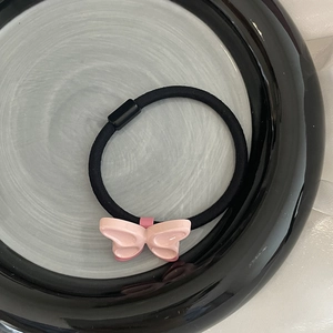 Élastique à cheveux papillon rose mignon avec cordon noir sur plat céramique