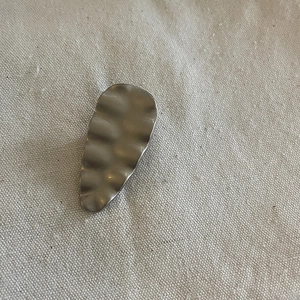 Detailed view of silver wave-textured metal hair clip on rustic burlap background