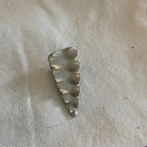 Detailed macro view of the silver wavy metal hair clip on a white textured fabric background