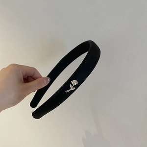 Close-up of black matte headband featuring a detailed golden rose metal ornament