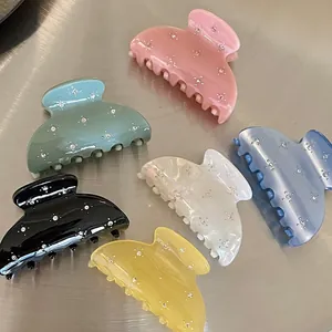 Close-up of mini hair claws with colorful rhinestones on a brushed metal surface