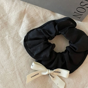 French vintage black satin scrunchie with white bow ribbon on a linen texture background