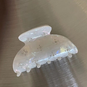 Detail of pearlescent white acetate hair claw with silver rhinestones and sturdy metal teeth