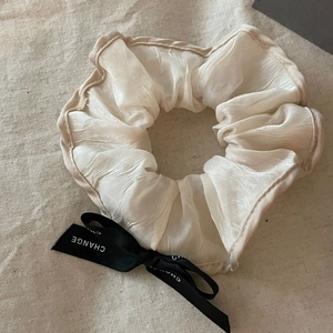 French vintage organza scrunchie with a black CHANGE ribbon bow on linen fabric