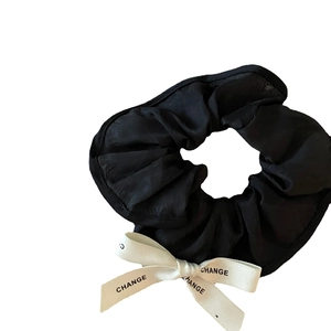 Vintage silk-texture scrunchie with a white bow featuring repeating black CHANGE lettering
