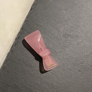 Nahaufnahme der durchsichtigen rosa Haarklammer aus Acetat mit goldener Aufschrift