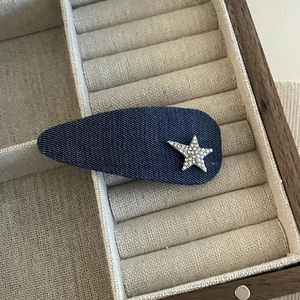 Detailed shot of dark blue denim star hair clip on a natural linen storage box display