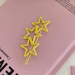 Barrette étoile jaune douce au fini mat sur fond de livre décoratif de couleur rose