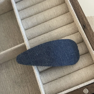 Denim star BB hair clip with dark blue twill fabric texture on a linen jewelry tray