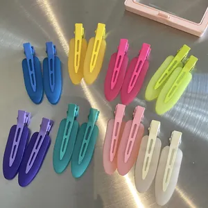 Flat lay of eight colorful matte seamless duckbill hair clips on metallic background