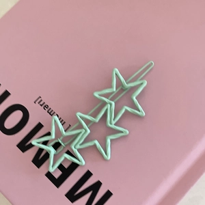 Détail d'une barrette à cheveux étoile vert menthe sur un livre rose, style mignon