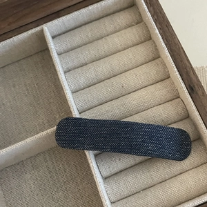 Close-up of a rectangular denim star BB hair clip placed in a rustic wooden jewelry box