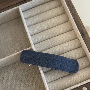 Close-up of a navy denim fabric star BB hair clip on a wooden jewelry box display