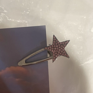 Close-up of a star-shaped hair clip with purple rhinestones on silver metal base