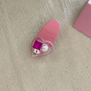 Detailed macro view of pink heart hair clip with magenta gemstone and white pearl