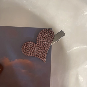 Detailed view of silver metal hair clip with densely inlaid pink rhinestones in heart shape