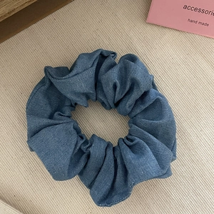 Vintage washed denim scrunchie in classic blue fabric shown on aesthetic background