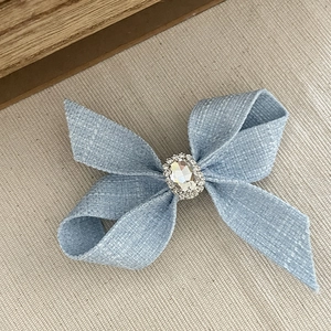 Dettaglio del fiocco per capelli in tessuto azzurro con cristallo ovale e piccoli strass