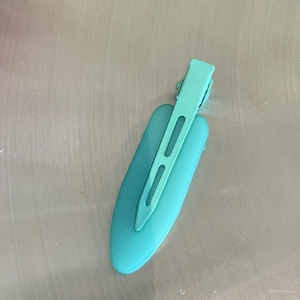 Detail of matte mint green seamless hair clip on industrial metal background