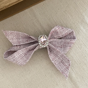 Dettaglio del fermaglio per capelli a fiocco in tweed rosa con cristallo e strass brillanti