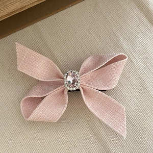 Dettaglio del fermaglio per capelli a fiocco in tweed rosa con cristallo ovale e strass