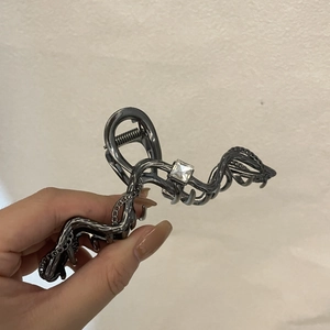Detail view of metallic snake-shaped hair claw clip with square zircon and fine chain