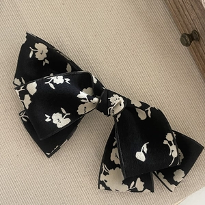Elegant floral bow hair clip with white flowers on black fabric for women's hairstyling