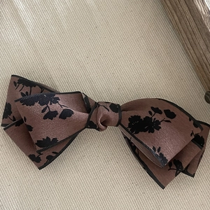 Detail of floral bow hair clip with black border and elegant pink fabric texture
