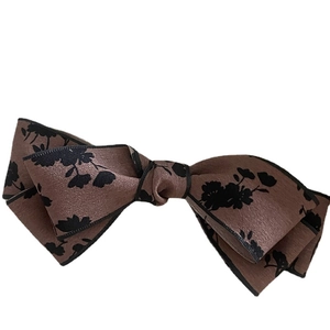 Elegant brown floral bow hair clip with black floral patterns and satin texture finish