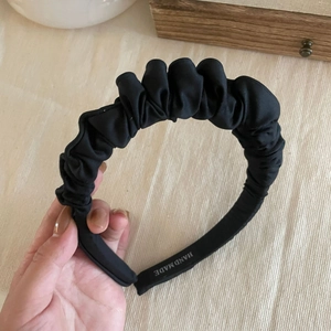 Close-up of handmade black pleated satin headband showing rich texture and thickness