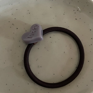 Dettaglio di un elastico per capelli nero con un ciondolo a cuore viola chiaro portafortuna