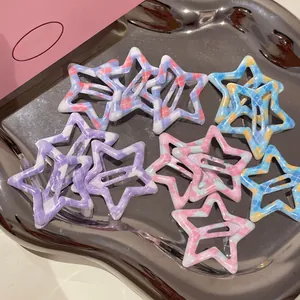 Détail de barrettes étoiles à motif vichy coloré disposées sur un plateau argenté