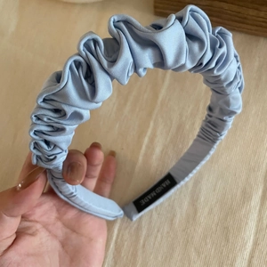 Light blue ruched fabric headband with premium satin finish and handmade woven label