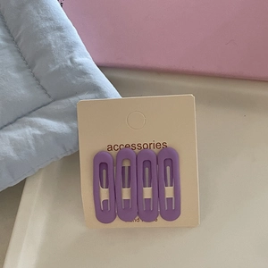 Detail of four matte purple teardrop BB hair clips on an accessories display card