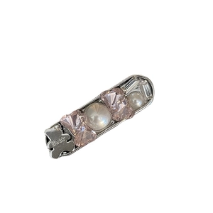 Pink gemstone hair clip with silver bear motif and white pearls on white background