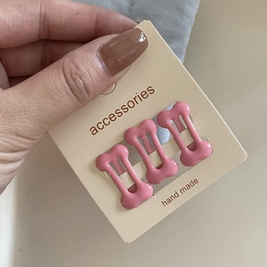 Detailed view of three pink bone-shaped hair clips on a handmade accessories card