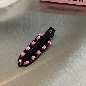 Barrette à cheveux en métal tissé ruban rose et noir sur surface argentée