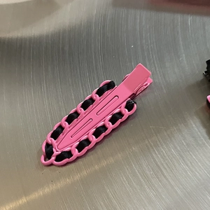 Barrette en métal rose avec ruban noir tressé et design de chaîne vue sous un angle de 45°