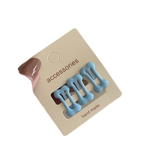 Set of three glossy light blue bone shaped hair clips for girls on a beige display card